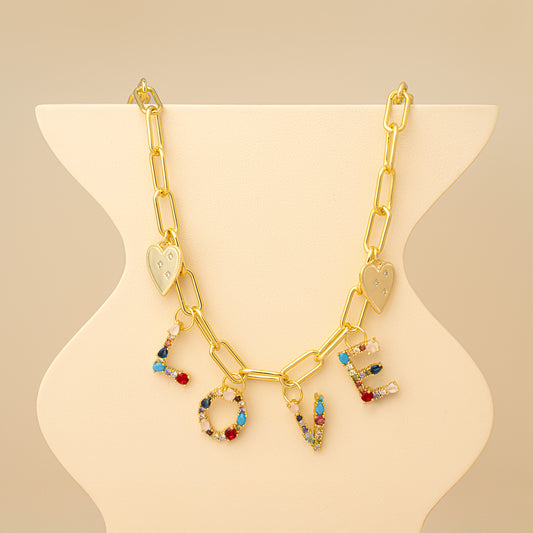 Gold necklace with 'LOVE' charms on a beige stand